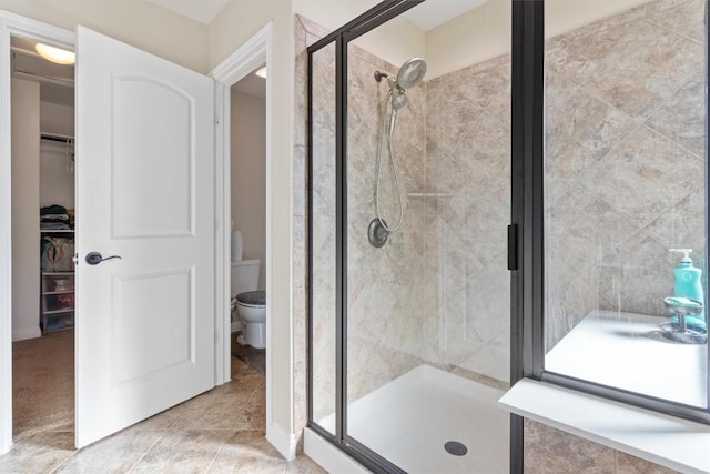 full bathroom featuring a walk in closet, a shower stall, and toilet