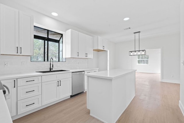 kitchen featuring stainless steel dishwasher, visible vents, light wood-style floors, a sink, and backsplash