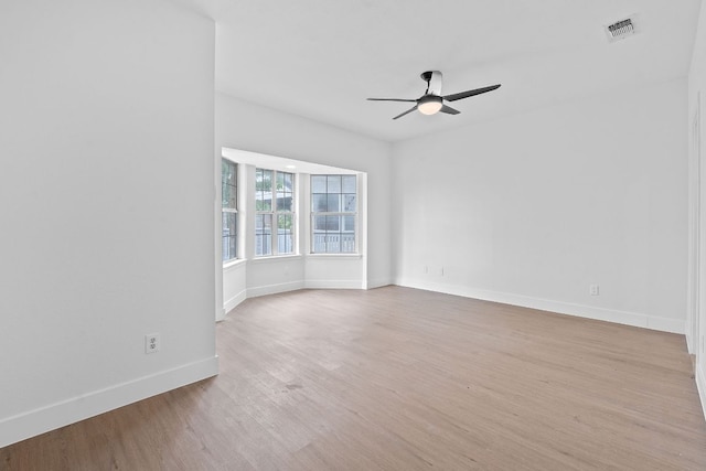 unfurnished room with light wood-style floors, baseboards, ceiling fan, and visible vents