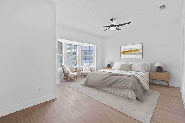 bedroom with baseboards, a ceiling fan, light wood finished floors, and visible vents