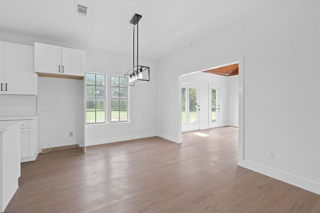 unfurnished dining area featuring light wood-style floors, baseboards, a chandelier, and visible vents