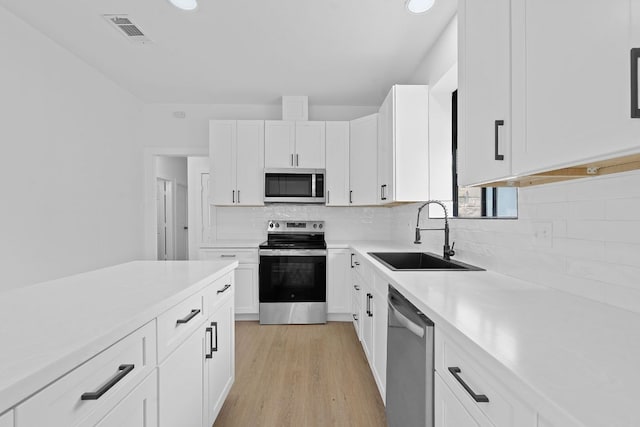 kitchen with decorative backsplash, visible vents, a sink, light countertops, and stainless steel appliances