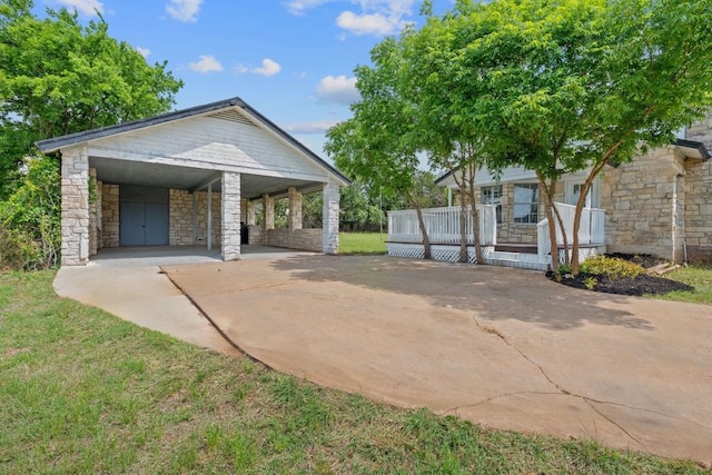 bungalow with covered porch, driveway, a carport, a front lawn, and stone siding