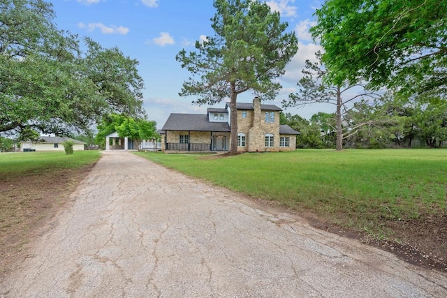colonial inspired home with a porch, a front lawn, aphalt driveway, and a chimney