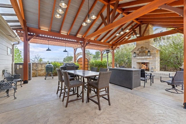 view of patio with an outdoor stone fireplace, a storage unit, a gazebo, an outbuilding, and outdoor dining space