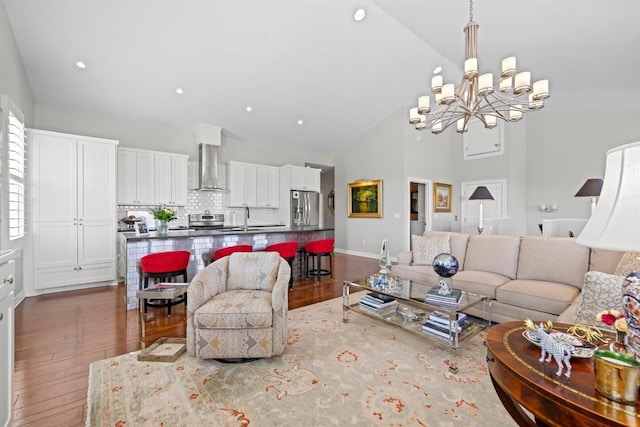 living area with a chandelier, hardwood / wood-style floors, baseboards, recessed lighting, and high vaulted ceiling