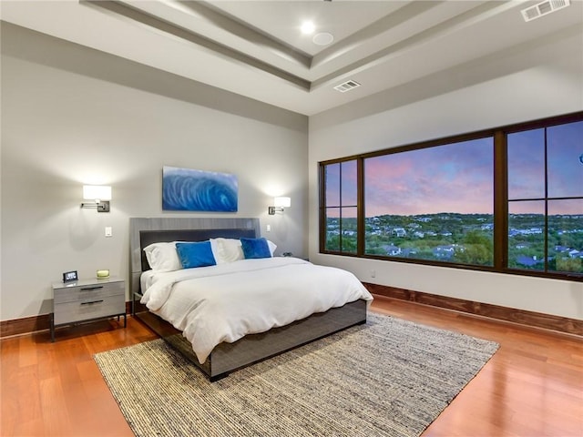 bedroom with visible vents, wood finished floors, and baseboards