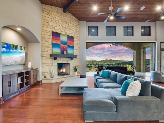 living room with a fireplace, high vaulted ceiling, a ceiling fan, wood ceiling, and wood finished floors