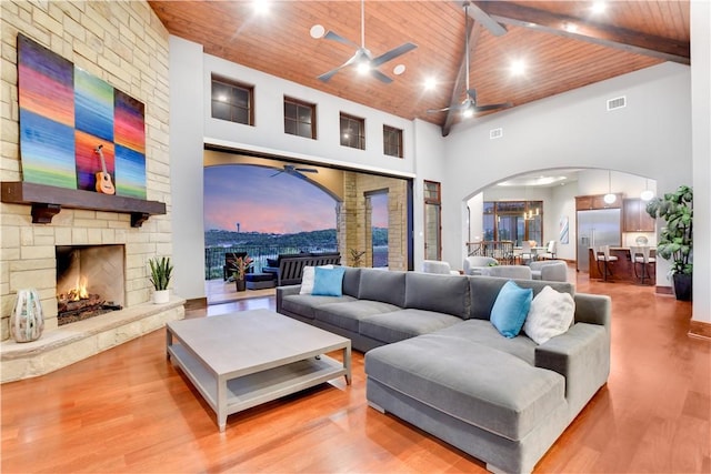 living area featuring arched walkways, wooden ceiling, wood finished floors, a ceiling fan, and high vaulted ceiling