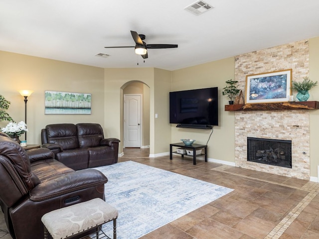 4525 Three Arrows Ct, Cedar Park, TX 78613 - living room with arched walkways, a ceiling fan, a stone fireplace, and baseboards