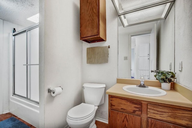 bathroom featuring toilet, bath / shower combo with glass door, wood finished floors, and vanity