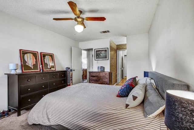 bedroom with a textured ceiling, visible vents, ceiling fan, and light colored carpet