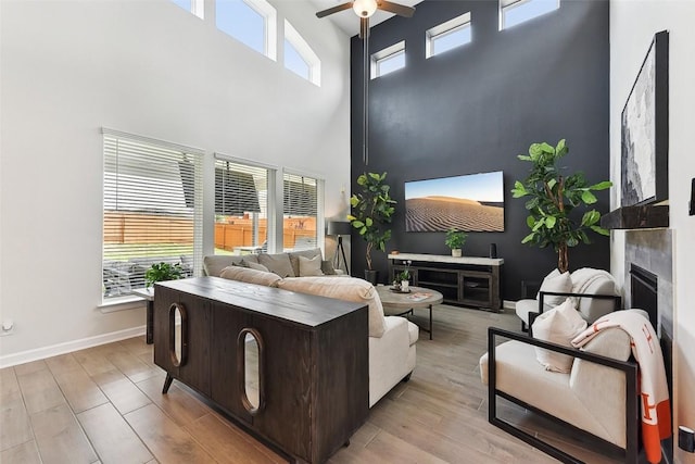 361 Wild Pecan Loop, Buda, TX 78610 - living area featuring a fireplace, ceiling fan, a towering ceiling, and light wood finished floors