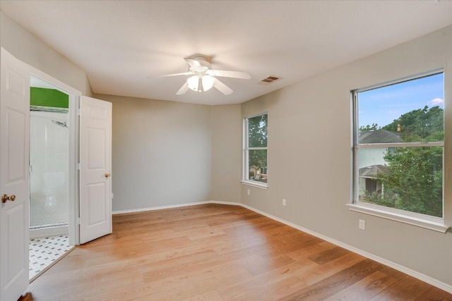 unfurnished bedroom featuring visible vents, baseboards, multiple windows, and light wood-type flooring