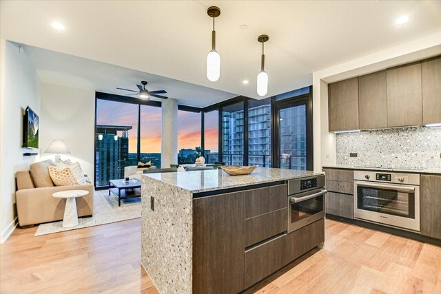 84 E Ave Unit 3909, Austin, TX 78701 - kitchen with open floor plan, modern cabinets, light wood-style flooring, and stainless steel oven