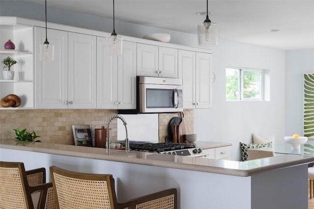 5707 Ave G, Austin, TX 78752 - kitchen featuring stainless steel microwave, open shelves, backsplash, and white cabinets