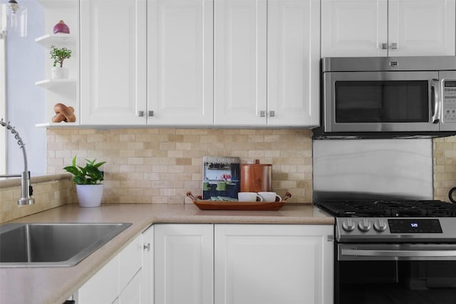 5707 Ave G, Austin, TX 78752 - kitchen featuring stainless steel appliances, decorative backsplash, white cabinets, and a sink