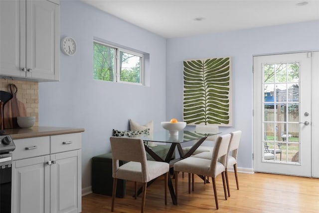 dining space featuring light wood-type flooring, baseboards, and a healthy amount of sunlight