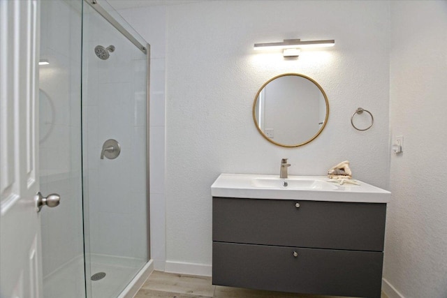 2208 Mimosa Trl, Round Rock, TX 78664 - bathroom featuring a shower stall, wood finished floors, vanity, and baseboards