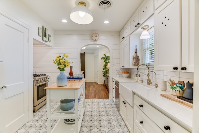 kitchen with white cabinetry, a sink, a barn door, stainless steel appliances, and butcher block counters
