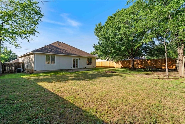 back of property with a fenced backyard, cooling unit, and a yard