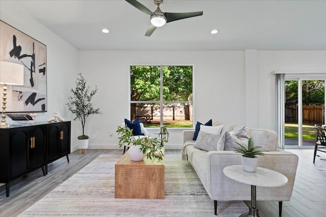 living room with baseboards, light wood-type flooring, ceiling fan, and recessed lighting