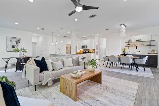 living area featuring visible vents, a ceiling fan, light wood finished floors, and recessed lighting