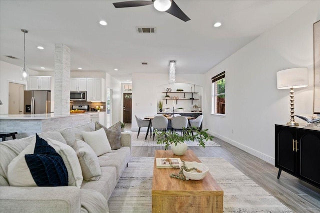 living room featuring recessed lighting, light wood-style flooring, baseboards, visible vents, and a ceiling fan