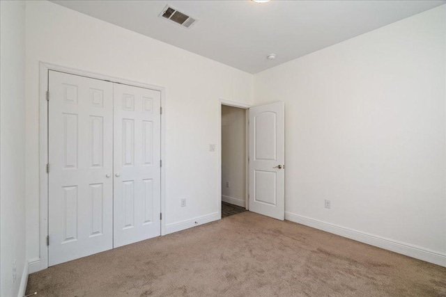 unfurnished bedroom with baseboards, visible vents, carpet floors, and a closet