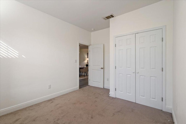 unfurnished bedroom with carpet, visible vents, a closet, and baseboards