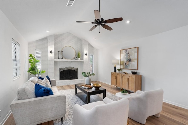 living room with a brick fireplace, visible vents, vaulted ceiling, and baseboards