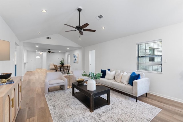 living area featuring visible vents, ceiling fan, light wood-style floors, and vaulted ceiling