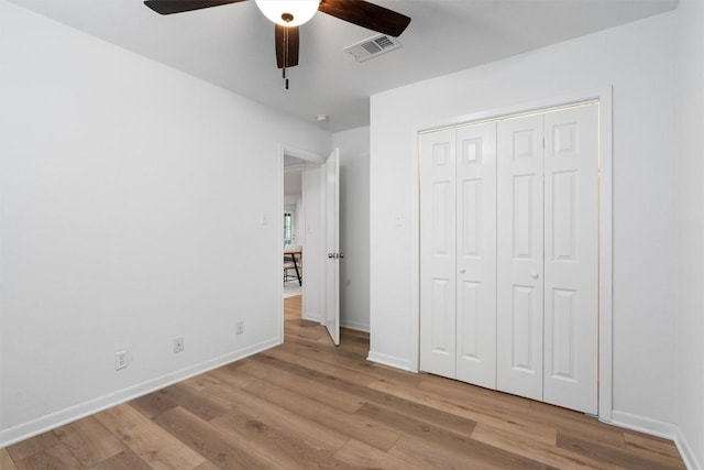 unfurnished bedroom with ceiling fan, visible vents, a closet, baseboards, and wood finished floors