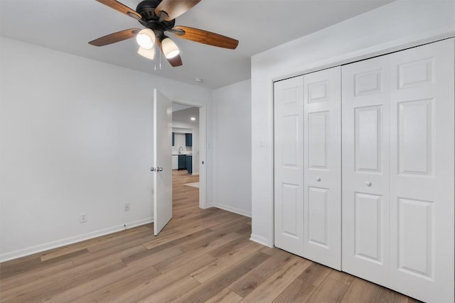 unfurnished bedroom with ceiling fan, a closet, light wood finished floors, and baseboards