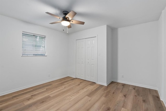 unfurnished bedroom featuring baseboards, ceiling fan, a closet, and light wood finished floors