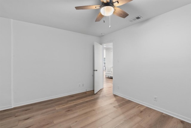 spare room featuring a ceiling fan, visible vents, wood finished floors, and baseboards