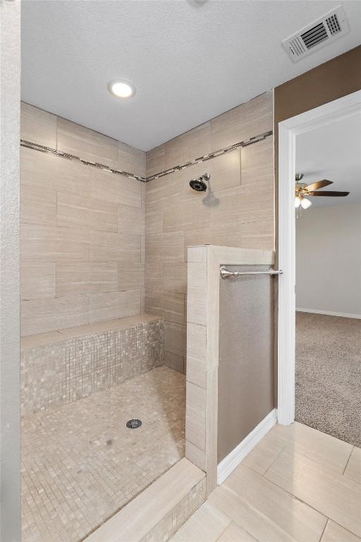 full bath featuring visible vents, ceiling fan, baseboards, and tiled shower