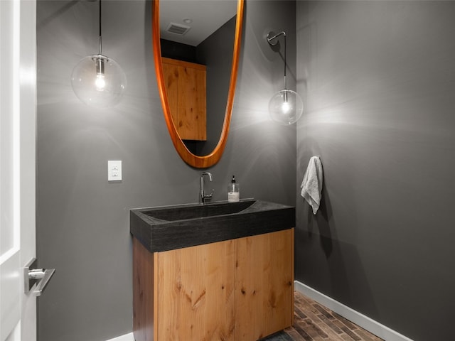 bathroom featuring wood finished floors, visible vents, vanity, and baseboards