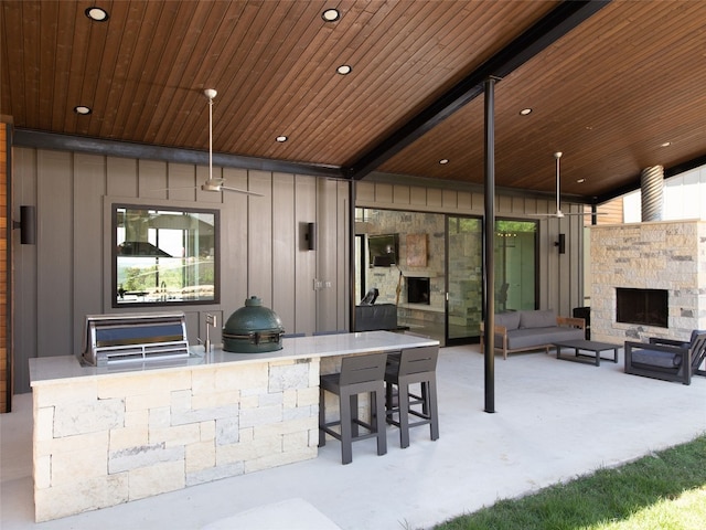 view of patio featuring area for grilling, an outdoor living space with a fireplace, and outdoor wet bar