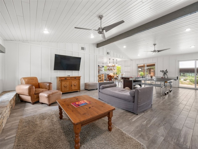 living room with wood finished floors, ceiling fan, and a decorative wall