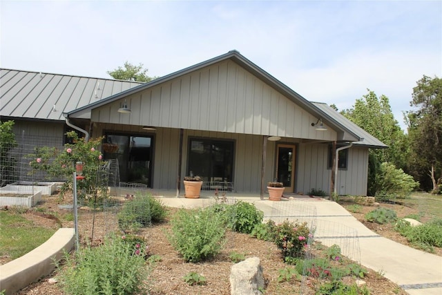 rear view of property with a standing seam roof, metal roof, and a porch