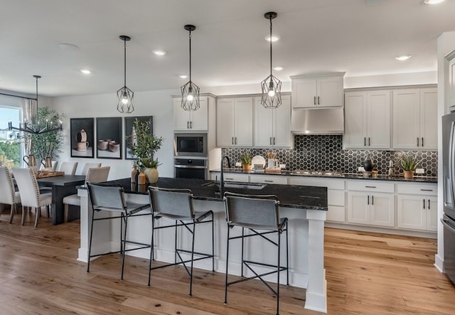 kitchen with a breakfast bar area, a sink, stainless steel appliances, and under cabinet range hood