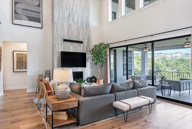 living area featuring a wealth of natural light, light wood-style floors, baseboards, and a high ceiling