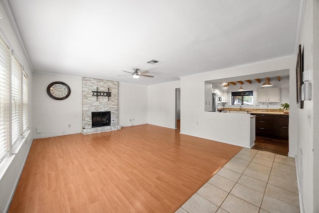 11811 Buggy Whip Trl, Austin, TX 78750 - unfurnished living room with ceiling fan, a fireplace, ornamental molding, and light wood-style floors