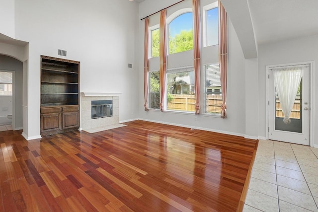 unfurnished living room featuring a high ceiling, visible vents, and a wealth of natural light