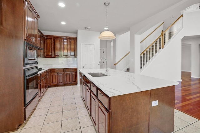kitchen featuring a sink, a kitchen island with sink, stainless steel appliances, recessed lighting, and light tile patterned floors