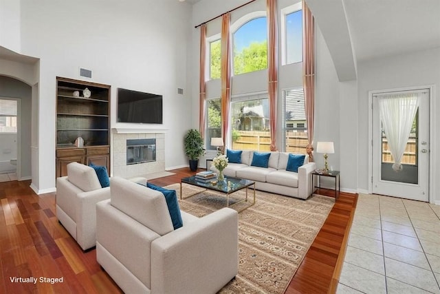 living room featuring baseboards, plenty of natural light, and a towering ceiling