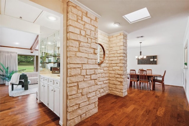 hallway featuring dark wood-style floors, an inviting chandelier, visible vents, ornamental molding, and a skylight