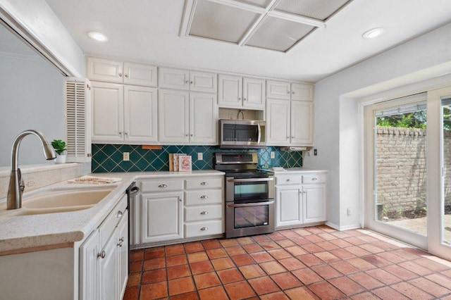 kitchen with white cabinets, stainless steel appliances, decorative backsplash, and a sink