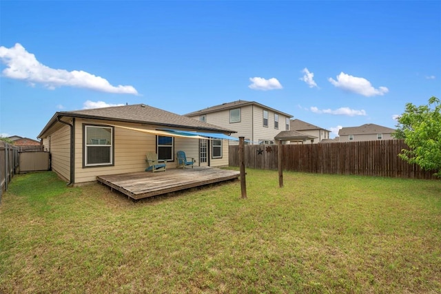 rear view of house featuring a lawn, a deck, and a fenced backyard